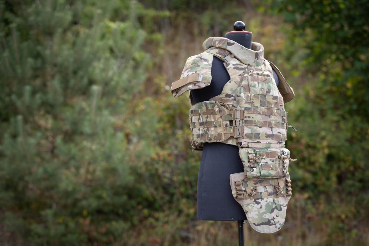 Een groengevlekt scherfvest speciaal voor vrouwen, hangend aan een zwarte pasbuste.