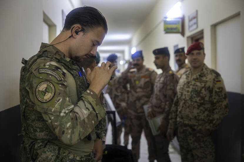 Nederlandse militair in een gang met op de achtergrond Iraakse en Duitse militairen.
