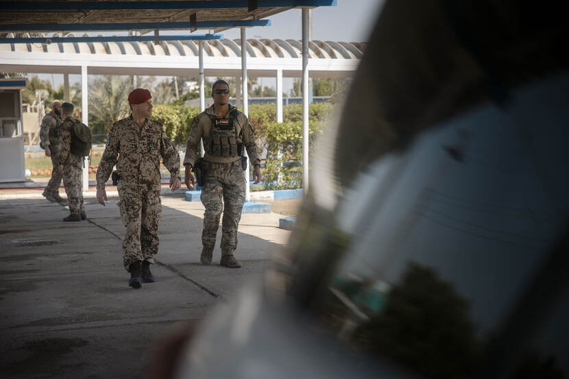 Duitse officier met een Nederlandse bodyguard loopt richting auto.