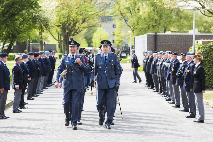 Militairen in het nette pak staan in twee rijen opgesteld en tussendoor lopen eveneens militairen.