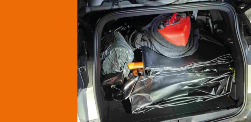 Geopende achterbak van een auto, met daarin een rubberboot en jerrycan.