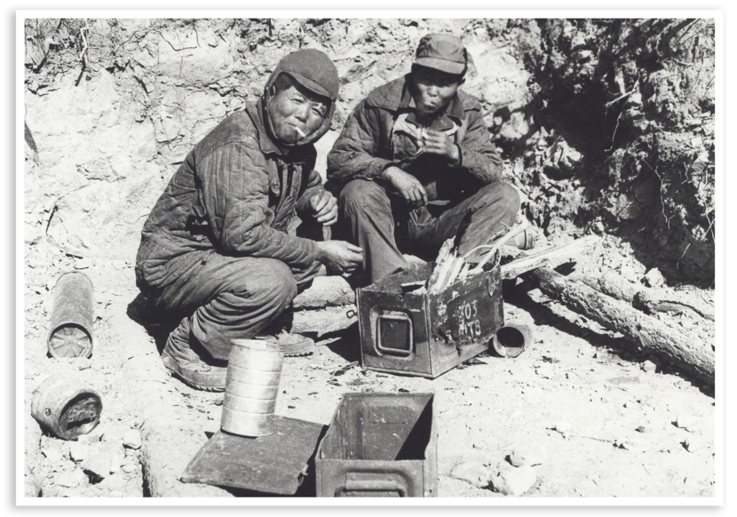 Twee Zuid-Koreaanse militairen van het Civil Transport Corps (CTC), ingedeeld bij het Nederlands Detachement Verenigde Naties in Korea, proberen een vuurtje te stoken in een lege munitiekist.