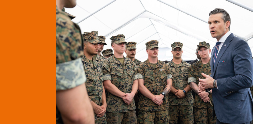 Defensieminister Pete Hegseth draagt een blauw pak en spreekt Amerikaanse militairen toe.