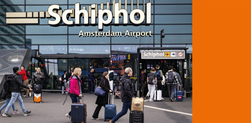 Passagiers met bagage lopen voor de ingang van luchthaven Schiphol.