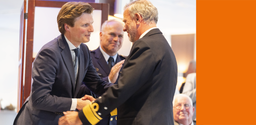 De minister en een hoge militair schudden elkaar de hand.