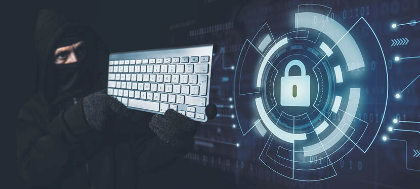 Een man in zwarte bivakmuts richt een toetsenbord alsof het een geweer is.