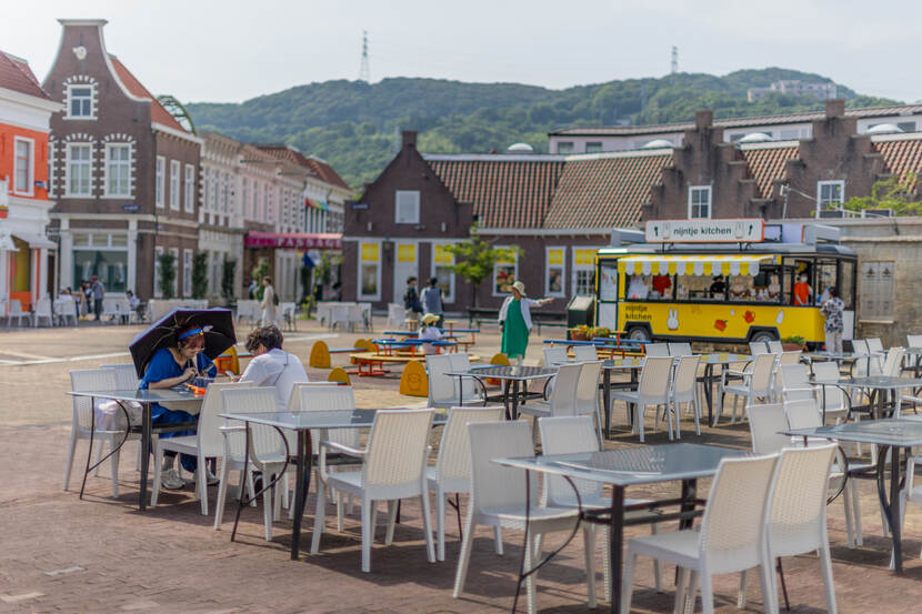 Een pleintje in het Japanse plaatsje Huis ten Bosch, met op de voorgrond stoeltjes waarop 2 Japanners zitten.