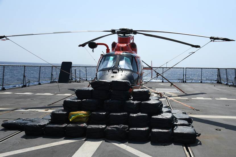 Een helikopter staat op het helidek van Zr.Ms. Groningen. Op de voorgrond ligt de grote drugsvangst.
