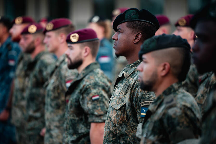 In de houding staande militairen met op de voorgrond enkele leden van de Caribische militairen.