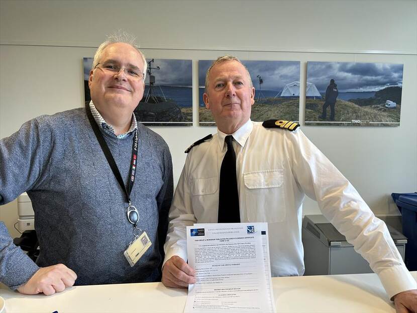 Een teamlid en overste Blank met een document dat de prijstoekenning vermeld.