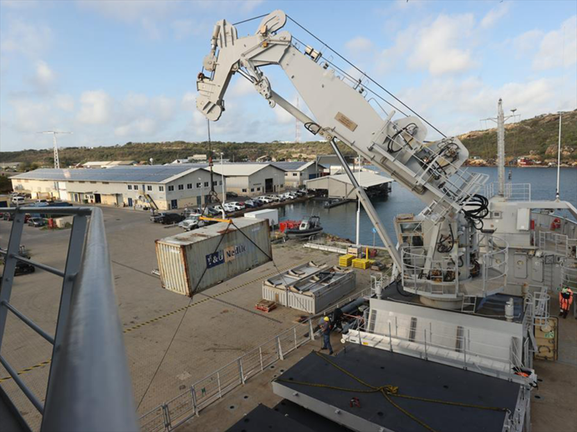 Een container wordt vanaf de wal aan boord gehesen van de Pelikaan.