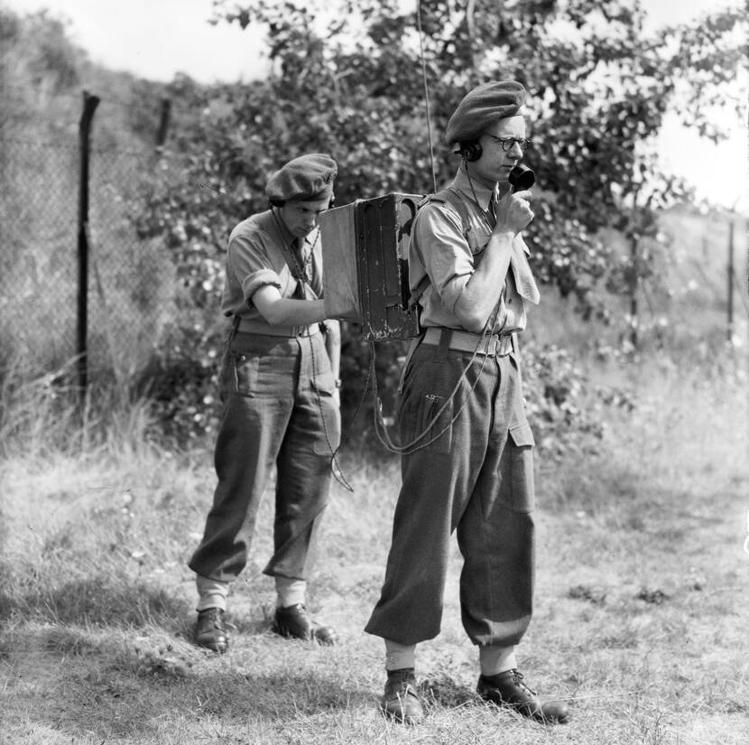 Op de foto twee militairen die met een portable radio een boodschap versturen.
