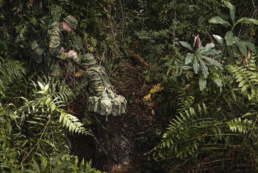 Militairen helpen elkaar in de jungle.