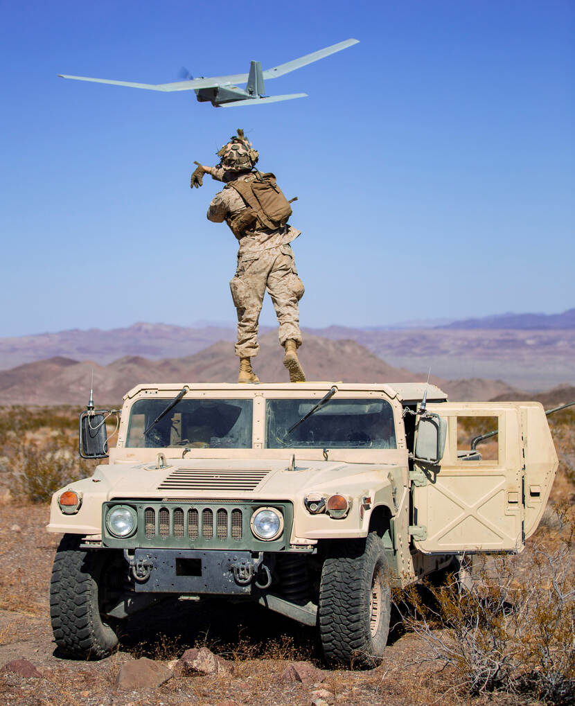 Een militair gooit een drone in de lucht.