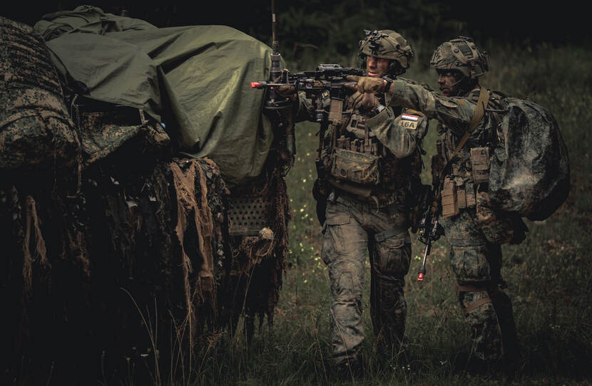 Militairen van 13 Lichte Brigade in overleg naast hun voertuig.