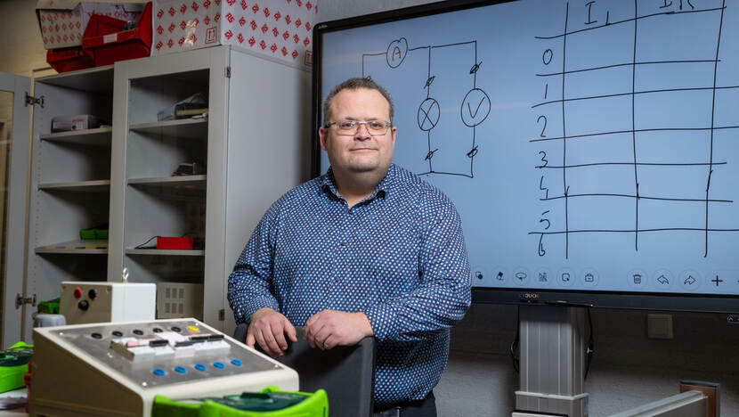 Op de foto Peter Ihmels staande in een klaslokaal met op de achtergrond een kast en een schoolbord.