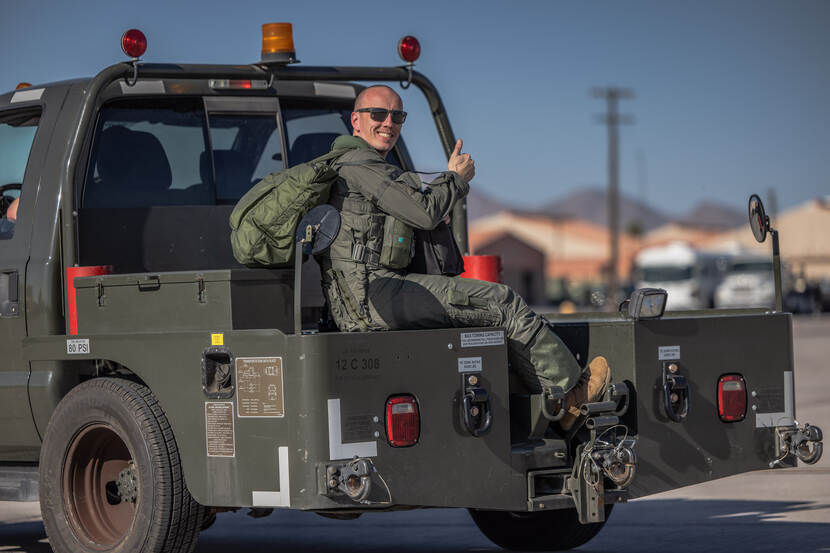 een vlieger die groet vanaf een rijdende vliegtuigtrekker.