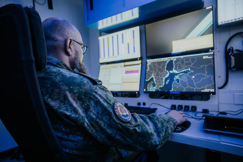 Een NDMC-specialist aan het werk voor een computerscherm met radarbeelden.