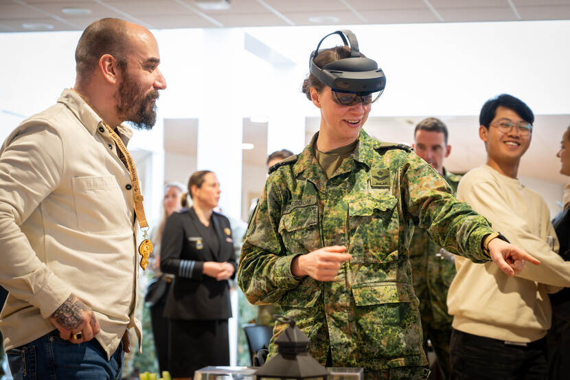 Tussen een aantal burger-medewerkers staat een militair met een AR-bril op