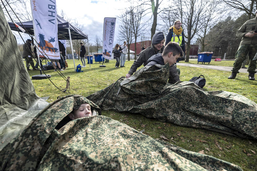 Twee bezoekers testen slaapzakken op het gras.