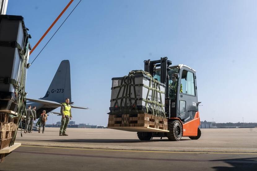 Links: Een Hercules staat op een platform terwijl een andere Hercules opstijgt. Rechts: Een vorkheftruck rijdt met een groot pakket naar een Hercules.