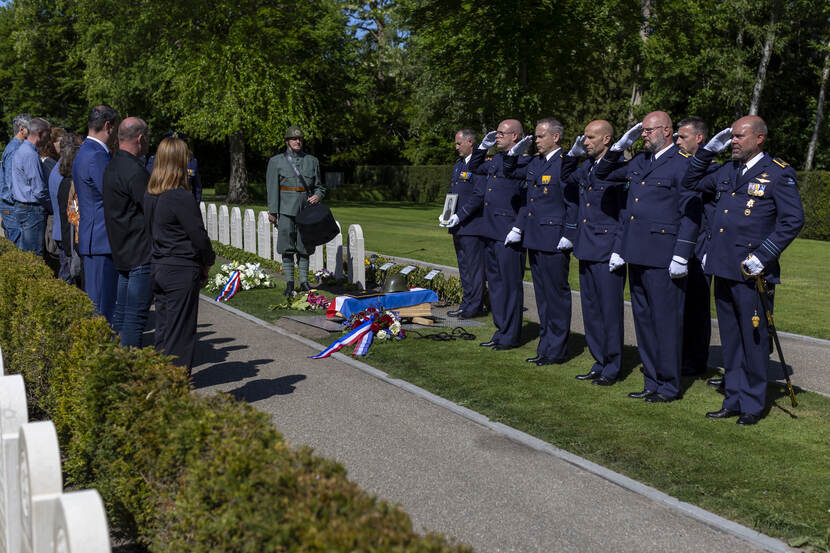 Uitvaartceremonie op de begraafplaats met daarbij de kist omringt door burgers en