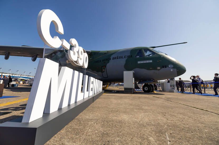 Embraer-transportvliegtuig met ernaast een decor van de woorden ‘C-390 Millenium’.