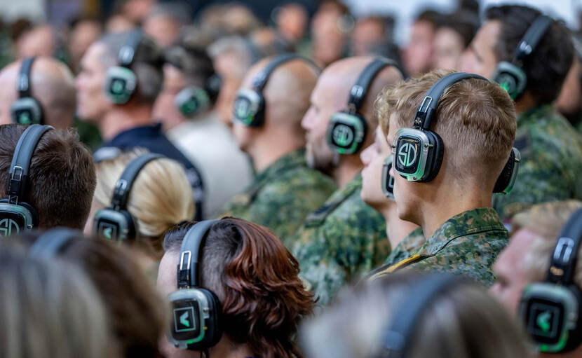 Militairen op de rug gezien met een koptelefoon op hun hoofd.