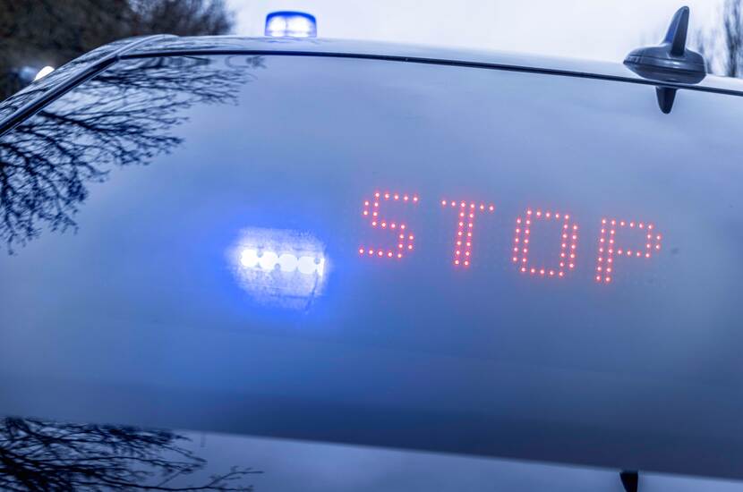 Stopteken in rode letters, gemonteerd in wagen van de Marechaussee.