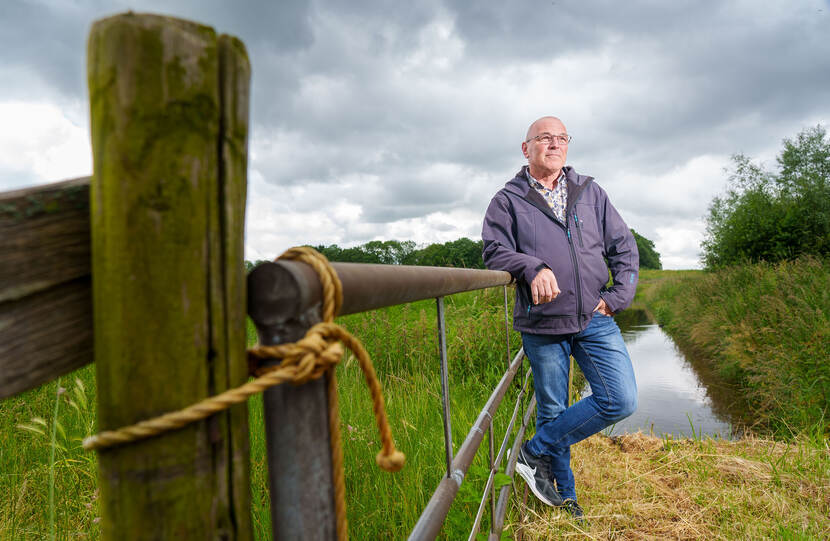 Portretfoto van Fred, leunend tegen een hek in een weiland.