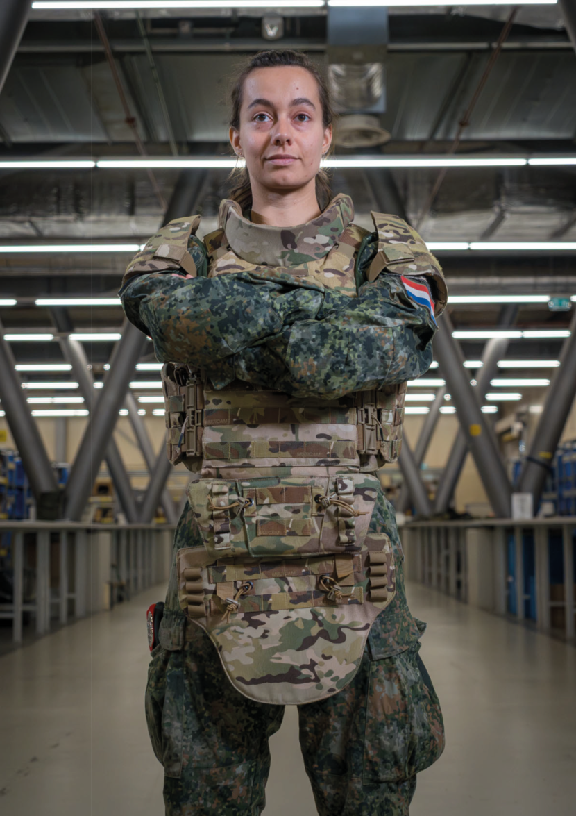 Een vrouwelijke militair draagt het scherfvest voor vrouwen. Haar armen zijn over elkaar.