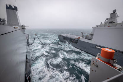 Zr.Ms. Karel Doorman en Zr.Ms. Johan de Witt op zee bij Zuid-Engeland. Een tankslang verbindt de schepen.
