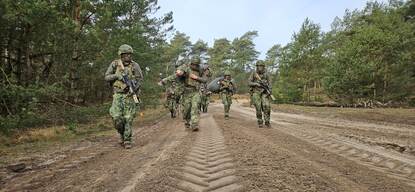 Een groepje reservisten doet verplaatsing te voet, waarbij een van de militairen een gewonden draagt.