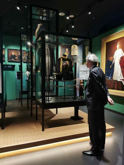 Man kijkt aandachtig naar vitrine vol kunstobjecten in Museum Bronbeek.