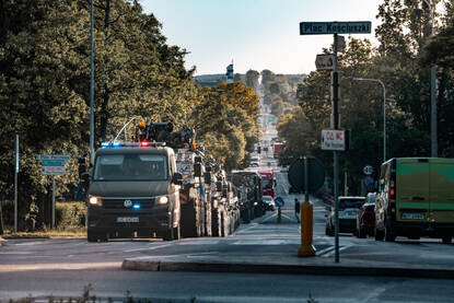 Diverse militaire voertuigen rijden in een lint door een Pools dorp.