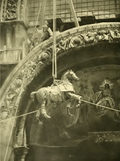 Sepia foto van een bronzen leeuw die in touwen in de lucht bungelt.