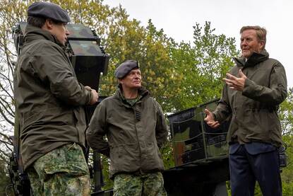 De koning luister in militair tenue naar een militair