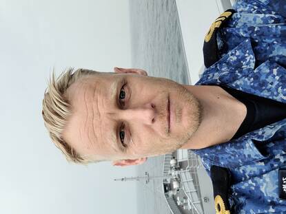 Een blond bemanningslid aan boord van een marineschip.