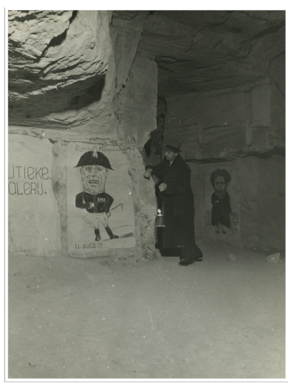 Een lid van het Nederlandse verzet toont een spotprent op de muur in de grotten bij Valkenburg (L) in 1944.