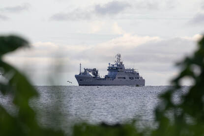 Links de Pelikaan op zee. Rechts waden mariniers vanaf een landingsboot naar het strand.