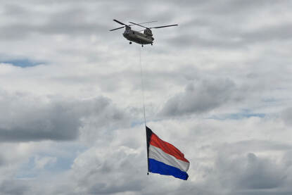 Twee foto’s van een helikopter met daaronder de Nederlandse vlag