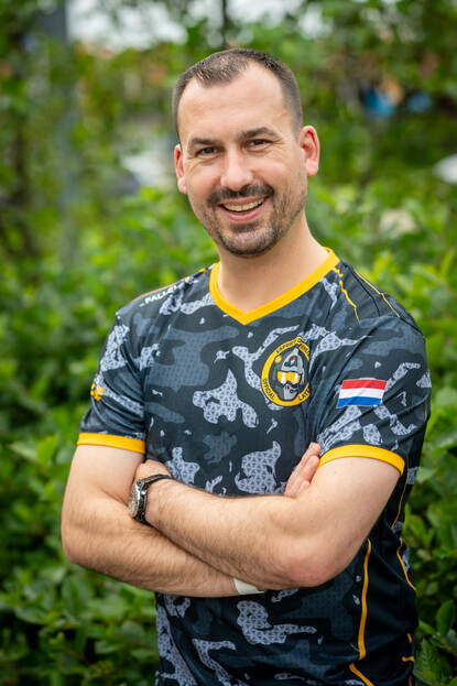 Militair kijkt lachend in de camera met de handen over elkaar.