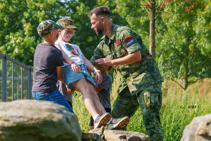 Een meisje springt van een steen en een meisje laat zich achterover vallen.
