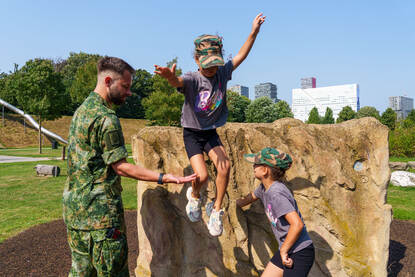 Een meisje springt van een steen en een meisje laat zich achterover vallen.