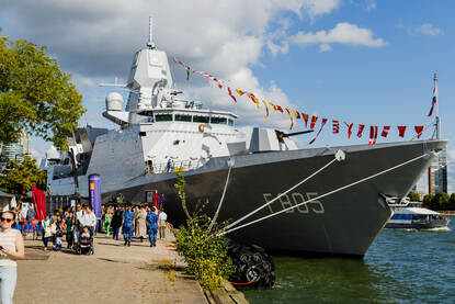 Een schip ligt aan de kade, mensen betreden het.