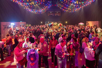 Feestelijk verlichte zaal vol mensen.