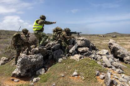 Een gevechtschietinstructeur geeft aanwijzingen aan een mitrailleurschutter. Naast hen zijn uitkijk.