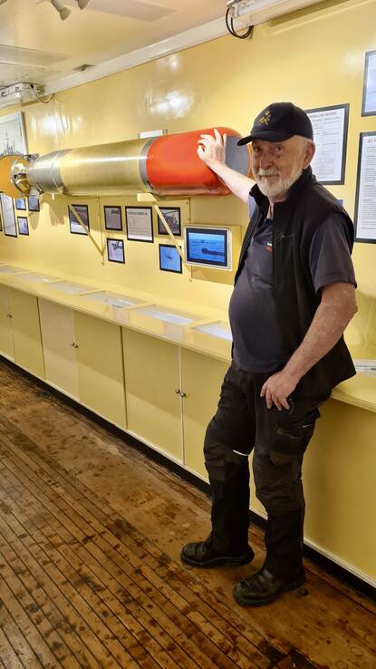 Rob Schouw, aan boord van de Mercuur, bij een model van een torpedo.