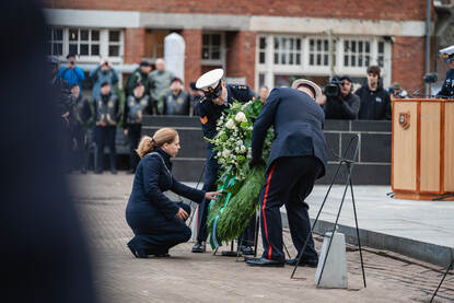 Links legt de Rotterdamse burgemeester Carola Schouten legt een krans bij ‘De Marinier’ en rechts een opname van Commandant Zeestrijdkrachten vice-admiraal Harold Liebregs die – geflankeerd door collega’s en buitenlandse hoogwaardigheidsbekleders – het defilé afneemt.