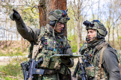 Een luitenant wijst naar het gebied voor zich, in gesprek met een andere militair.